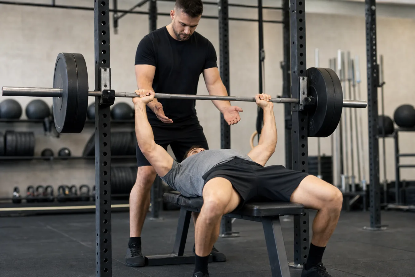 CrossFit athlete bench pressing under control with a coach spotting safely