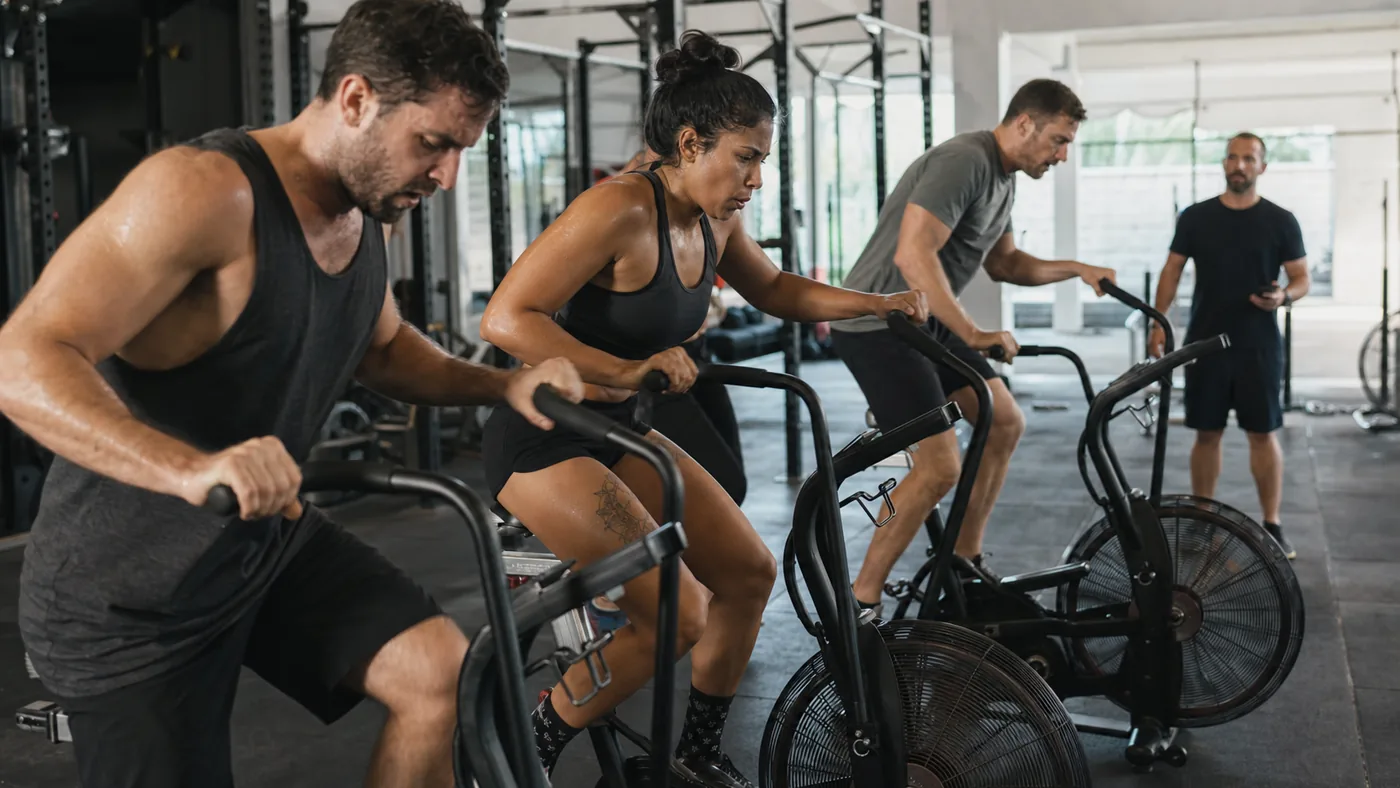 CrossFit athletes pacing air bikes during class intervals