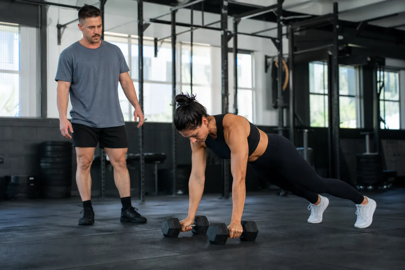 CrossFit athlete setting up for a dumbbell devil press in a functional fitness gym
