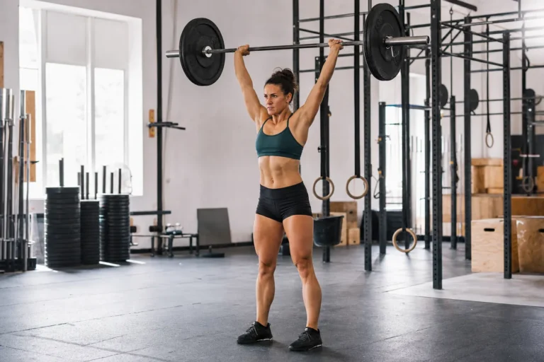 CrossFit athlete finishing a push press overhead in a training gym