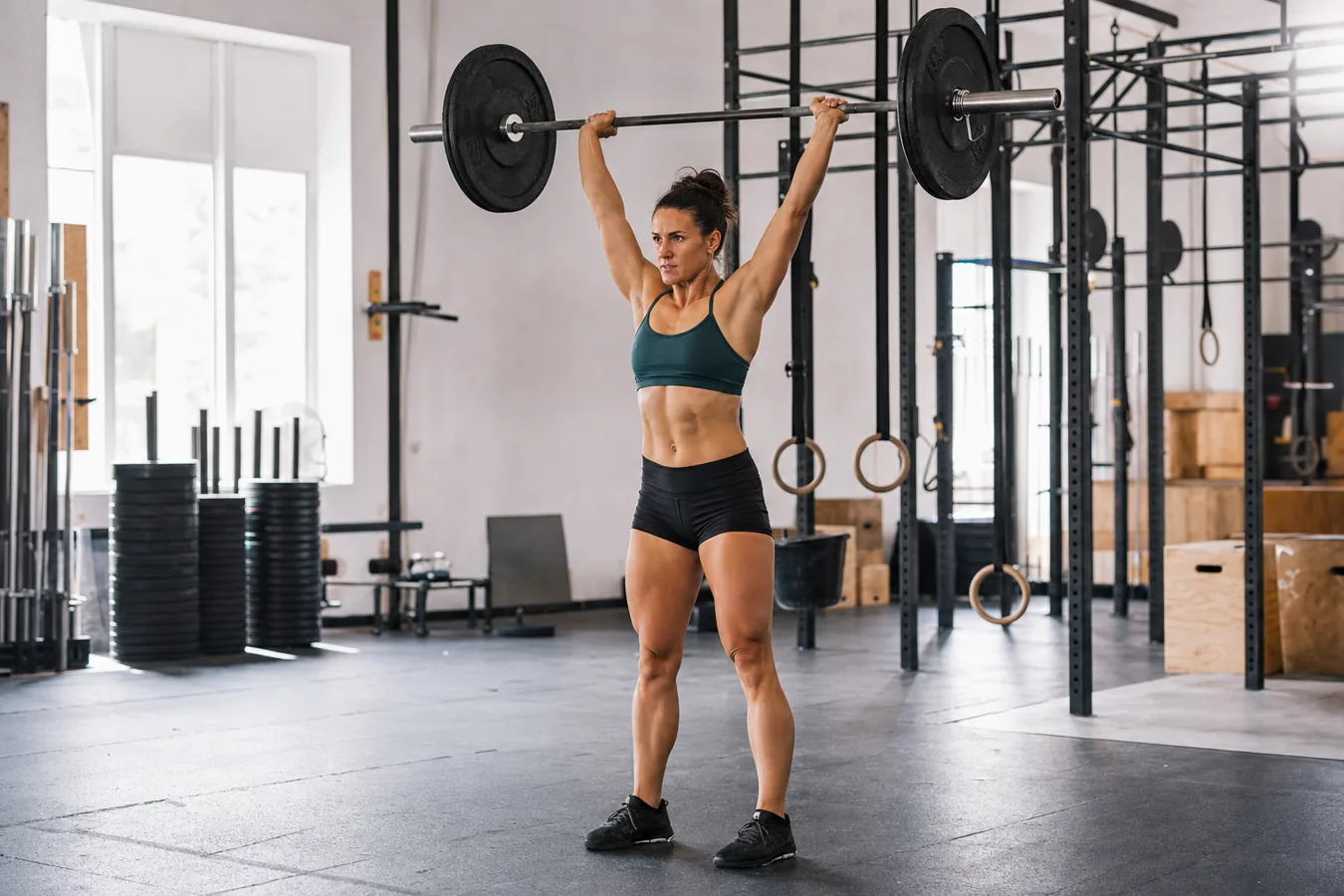 CrossFit athlete finishing a push press overhead in a training gym