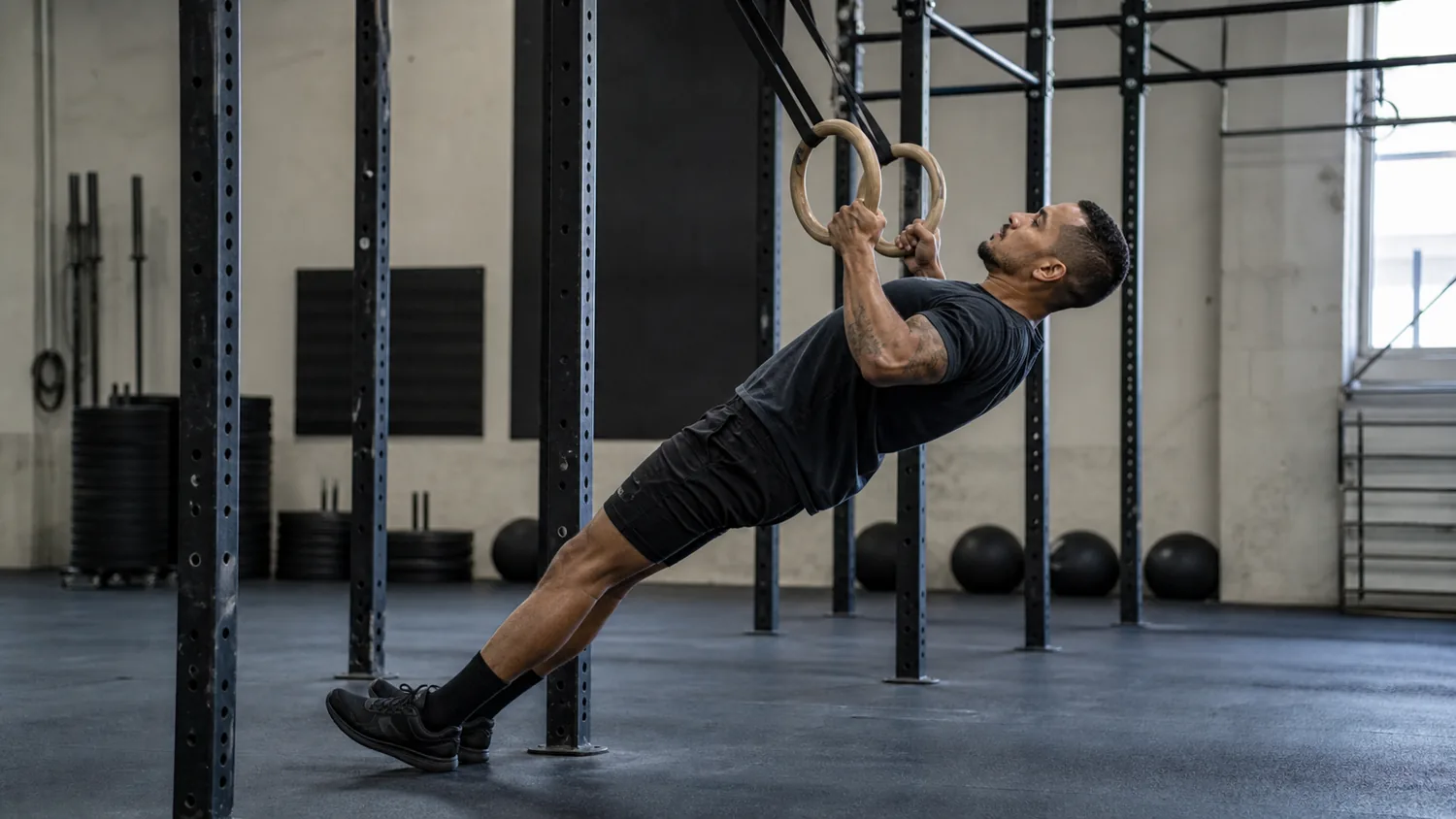 CrossFit athlete performing ring rows on gymnastic rings in a training gym