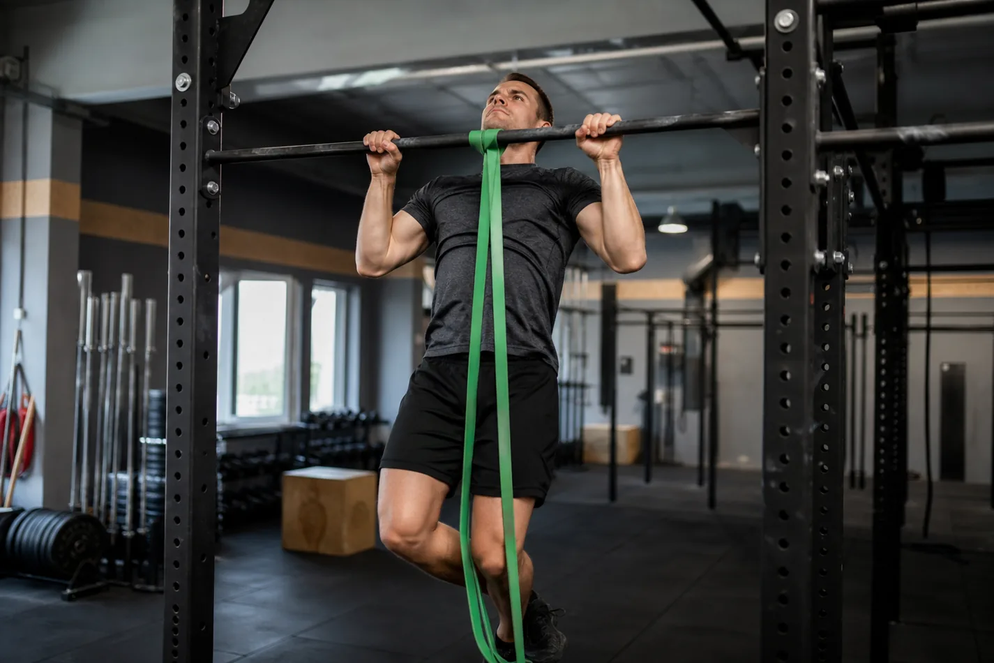 Athlete using a resistance band to scale chest-to-bar pull-ups in CrossFit