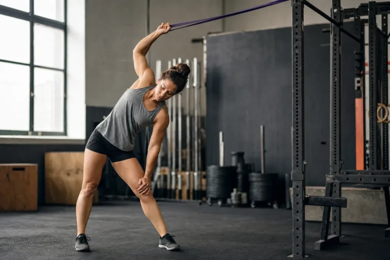 CrossFit athlete using a resistance band for a banded lat stretch in a gym