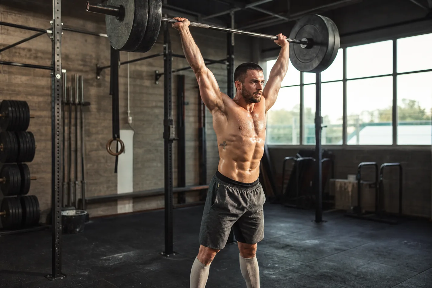 CrossFit athlete driving a barbell from front squat into overhead lockout during a cluster