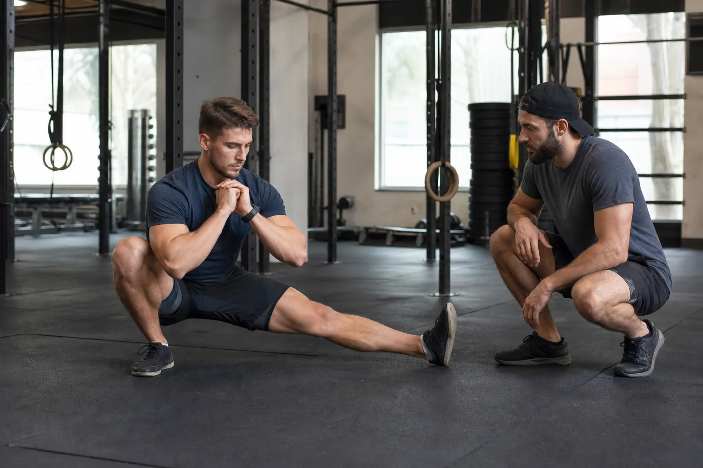 CrossFit athlete performing a controlled Cossack squat with coach checking alignment