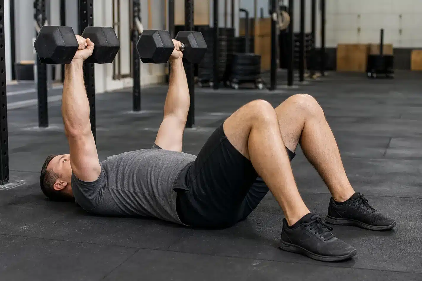 CrossFit athlete setting up a dumbbell floor press with neutral wrists