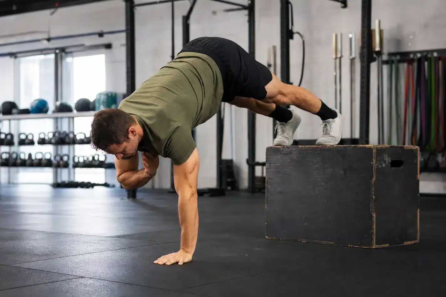 CrossFit athlete practicing scaled pike shoulder taps with feet on a box