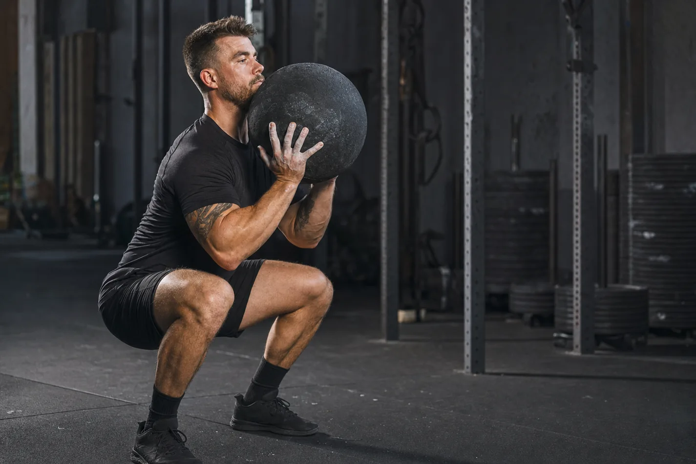 CrossFit athlete lifting a D-ball from the floor in a functional fitness gym