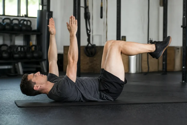 CrossFit athlete performing a controlled dead bug core drill on a gym mat