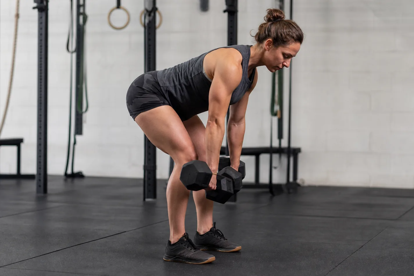 CrossFit athlete setting dumbbells close to the feet before a deadlift