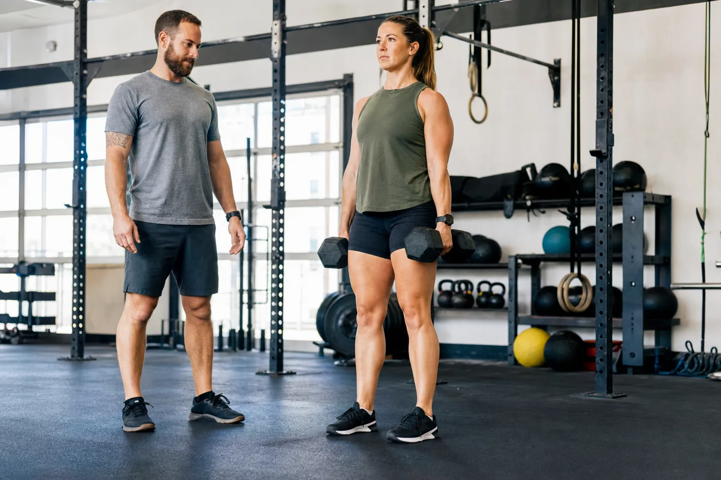 CrossFit athlete standing tall at the top of a controlled dumbbell deadlift