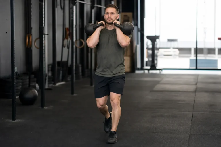 CrossFit athlete walking with two kettlebells in the front rack position
