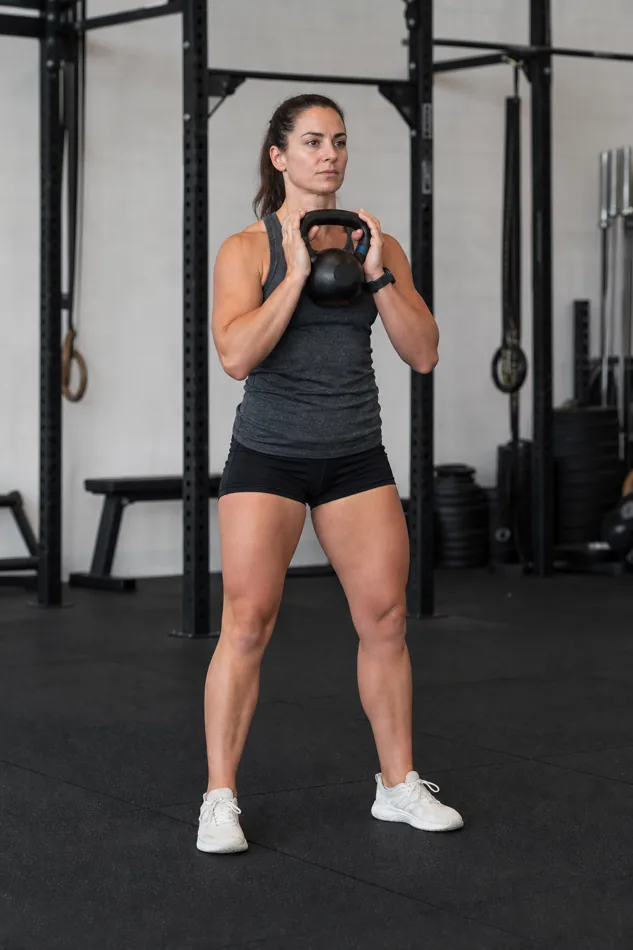 CrossFit athlete setting up for a kettlebell goblet squat with the bell held close to the chest