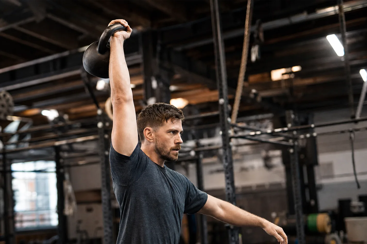CrossFit athlete performing a kettlebell snatch with a stable overhead lockout