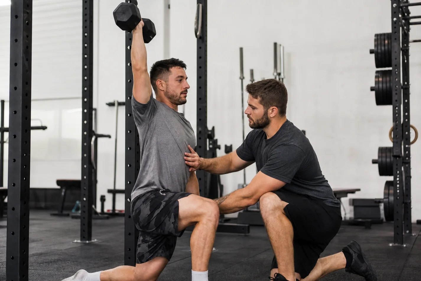 CrossFit athlete setting a stable dumbbell overhead lunge position