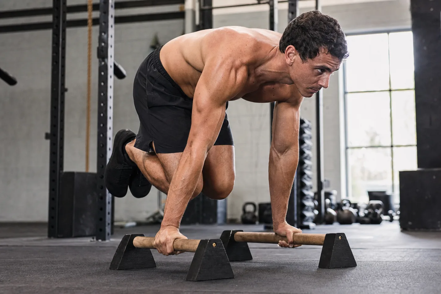 CrossFit athlete holding front support on parallettes before a shoot-through
