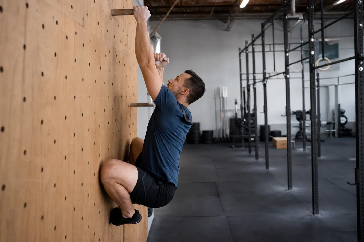 CrossFit athlete practicing a pegboard climb with controlled body position