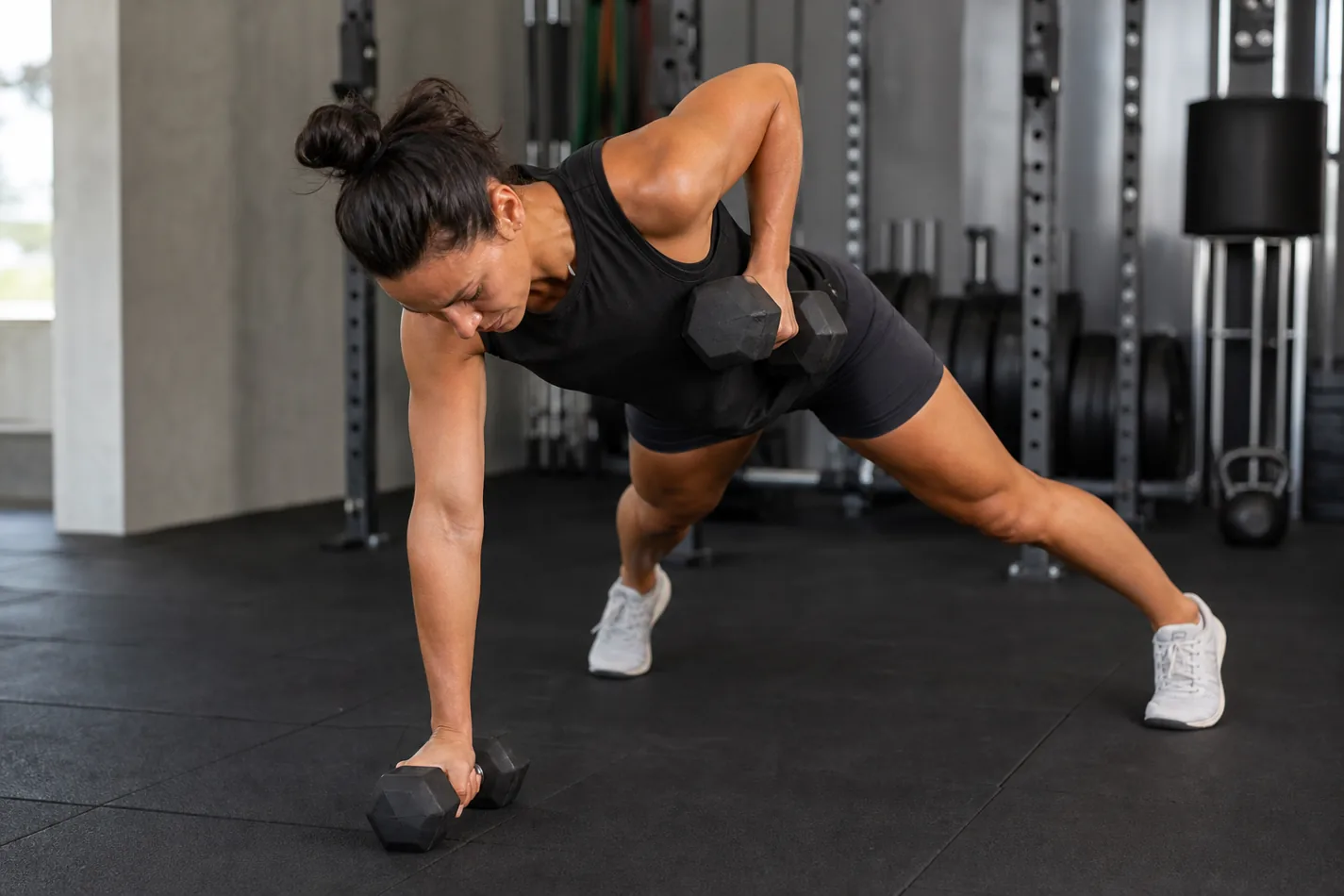 CrossFit athlete scaling a renegade row with wide feet and lighter dumbbells