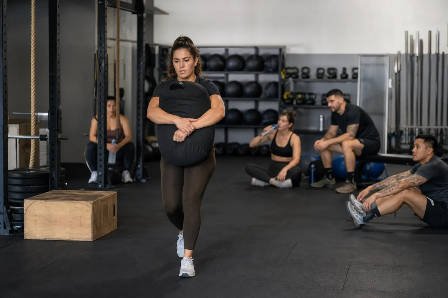 CrossFit athlete walking with a sandbag carry during a functional fitness class