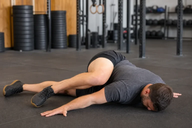 CrossFit athlete demonstrating a controlled scorpion stretch in a gym