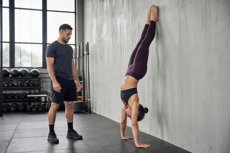 CrossFit athlete holding a strict handstand push-up position against a wall