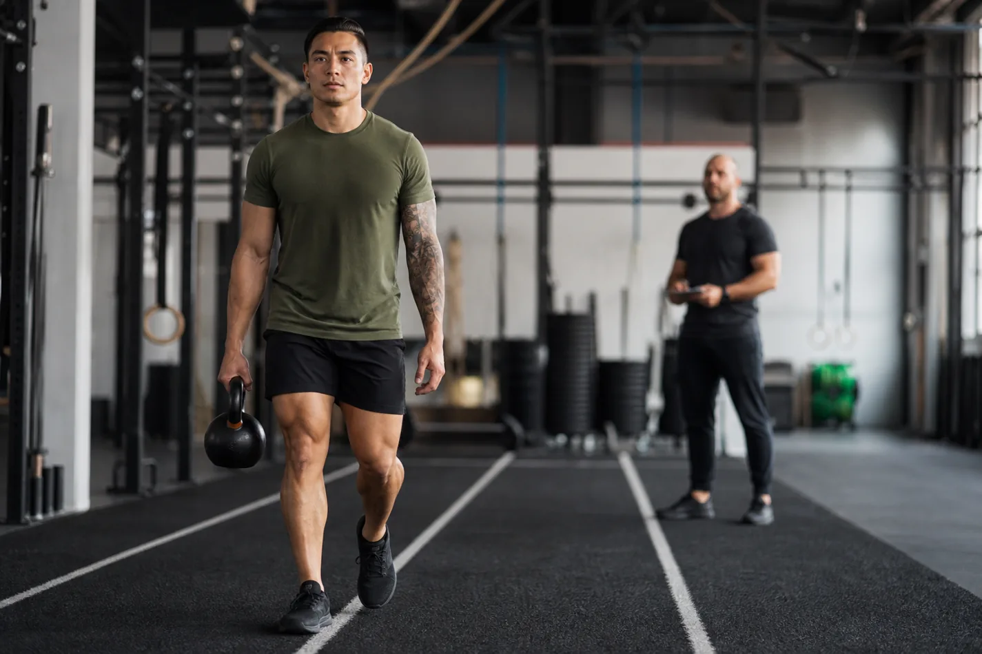 CrossFit athlete doing a single-arm suitcase carry with a kettlebell in a gym